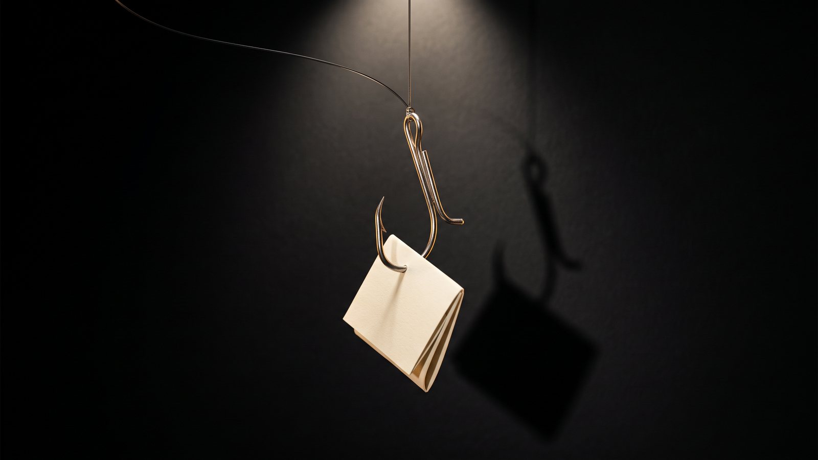A bent metal hook hanging on a fine line against a black background with a folded cream document caught on it like bait